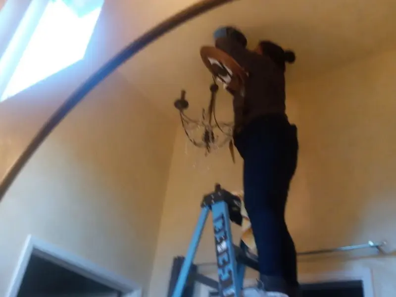 Electrician installing a chandelier in a Oak Park residence